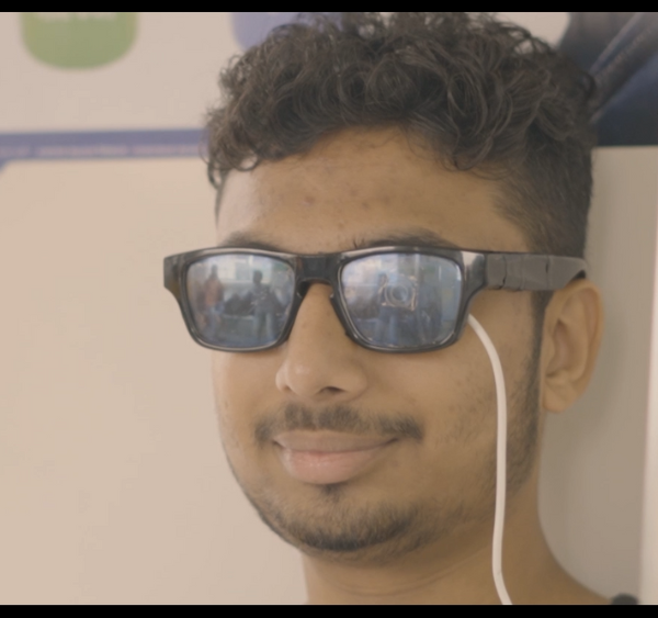 A headshot from the side of a person with the Drishti Glasses, they are tapping on the touchpad.